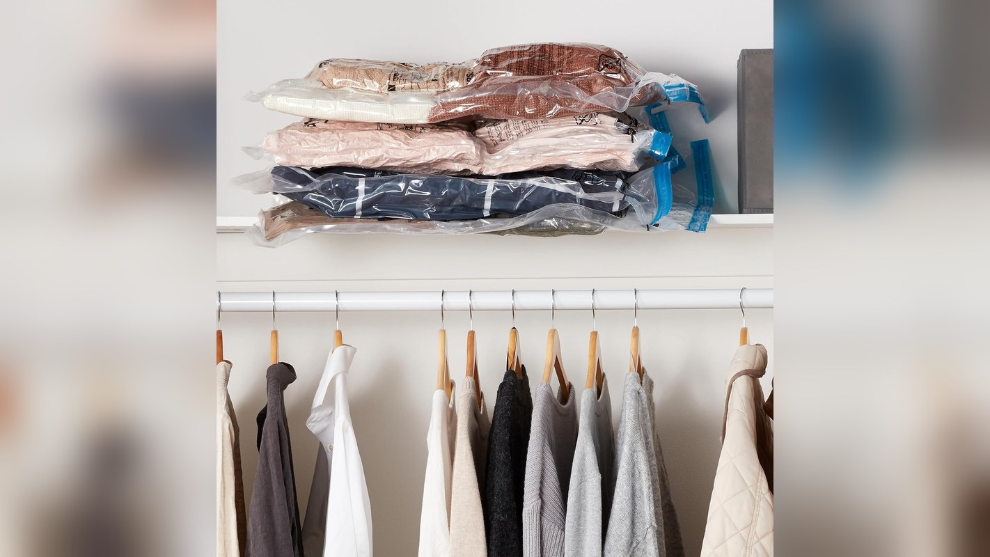 Folded clothes compressed in vacuum storage bags on a closet shelf