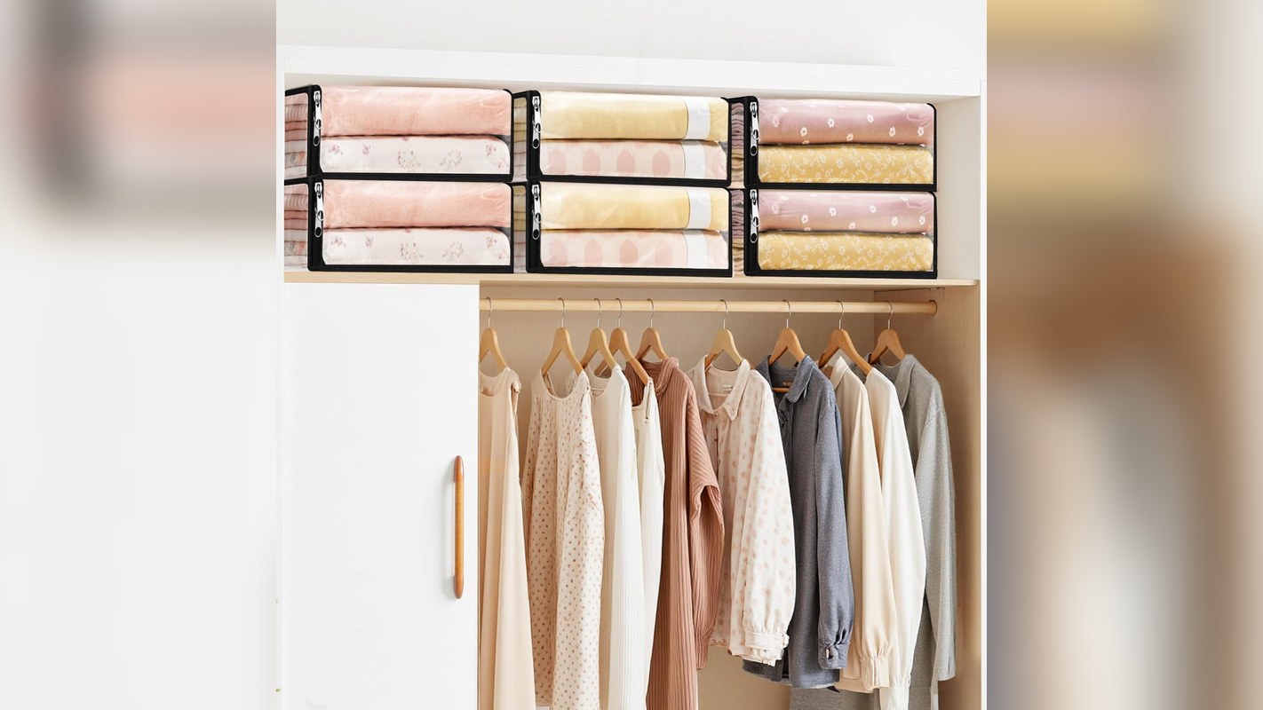 Clear zippered sheet storage bags holding folded sheets and towels on a shelf above hanging clothes