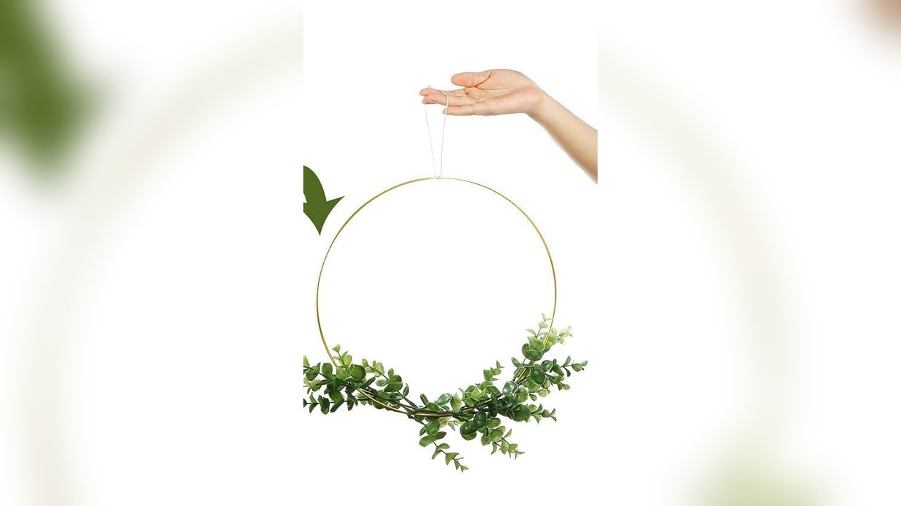 Gold metal hoop hanging from a string with greenery and ornaments