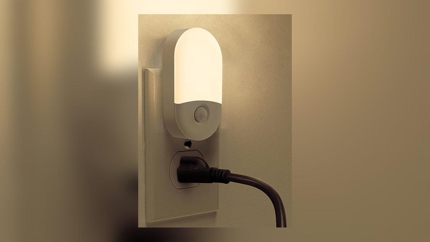 Warm plug-in motion sensor night light glowing on a wall outlet