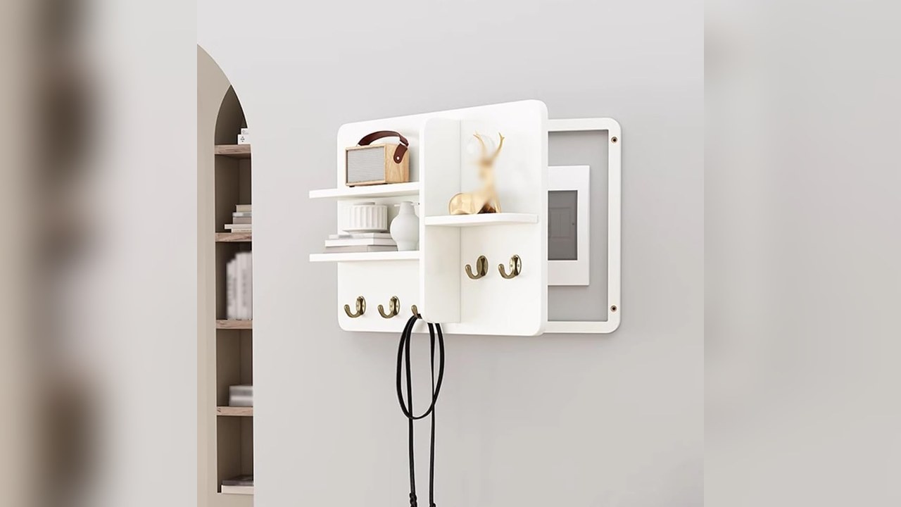 White wall-mounted breaker box cover with a small shelf, wooden cubby and gold hooks on a hallway wall