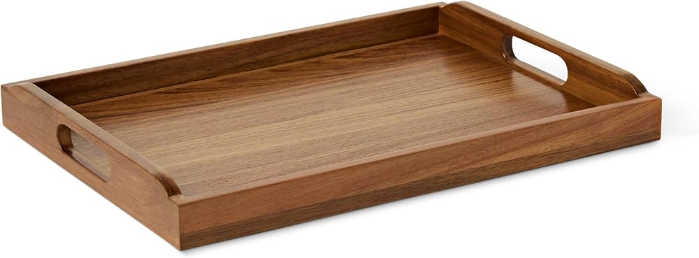 Acacia wood serving tray holding olive oil and a small plant on a kitchen counter
