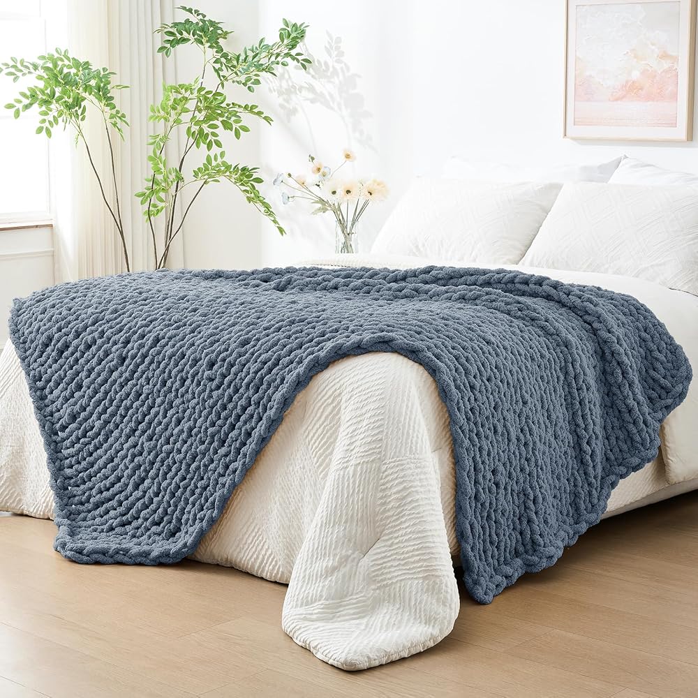 Chunky knit blue throw blanket folded across the foot of a bed
