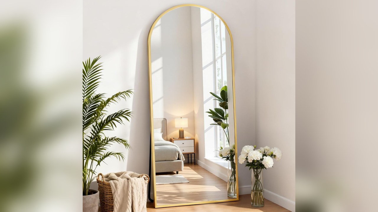 Tall arched floor mirror leaning against a living room wall