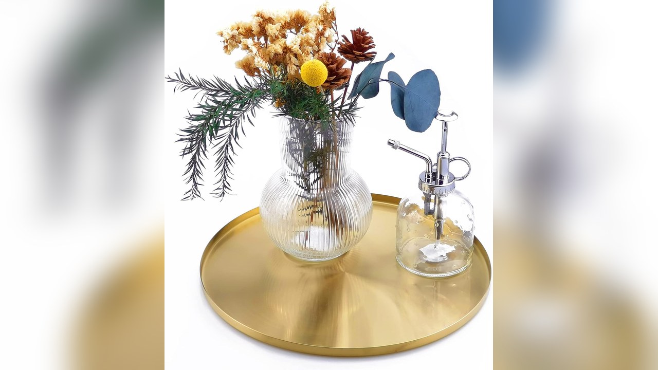 Round brushed gold tray holding drinks and a small vase of flowers