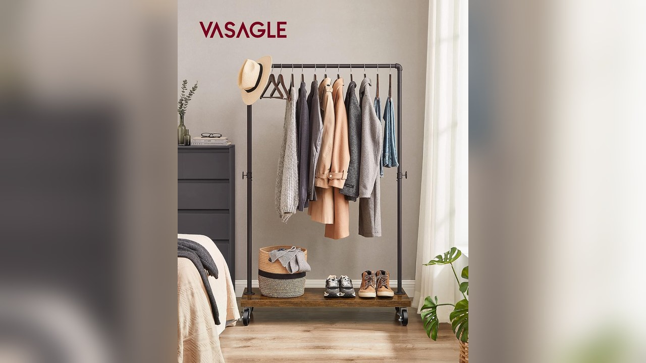Industrial style rolling clothes rack with hanging coats and a wood bottom shelf in a bedroom