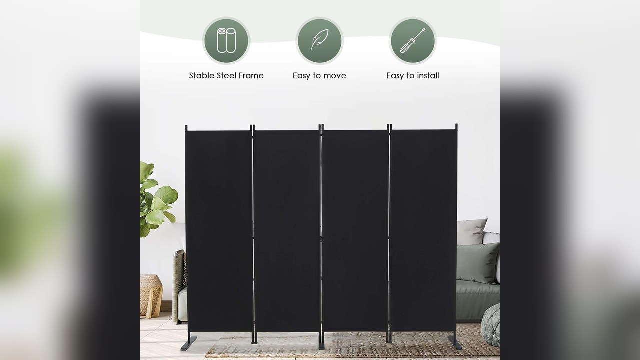 Black four-panel folding privacy screen standing in a bedroom separating a sleeping area