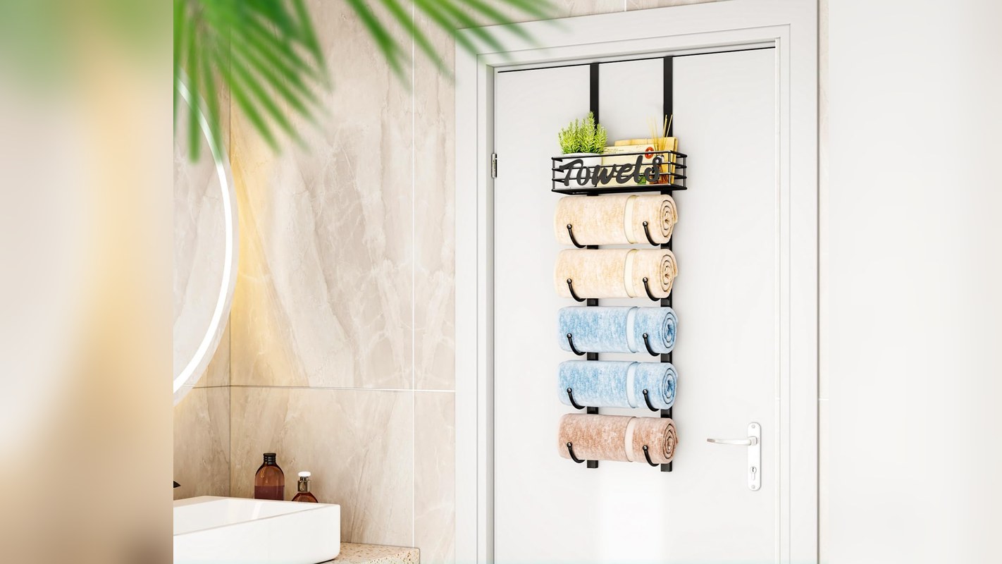 Over-the-door towel rack with six rolled towels and a top basket hanging on a bathroom door