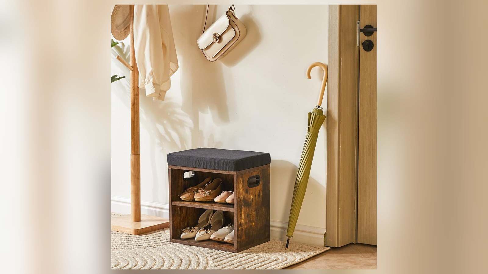 Small rustic brown shoe storage bench with padded seat holding flats next to coat stand and umbrella in entryway