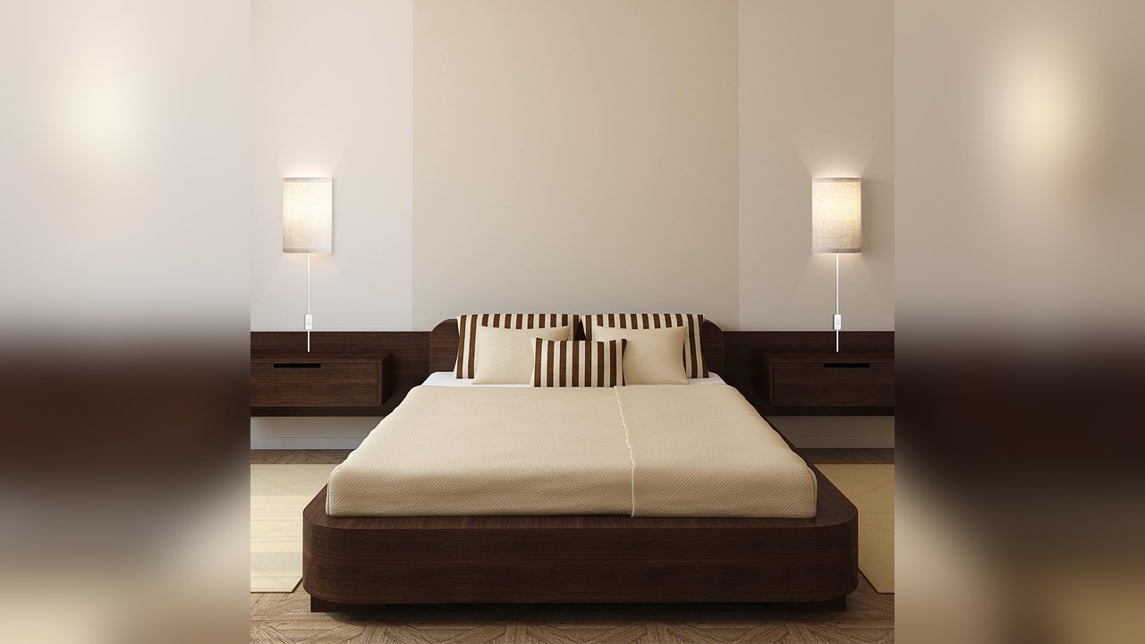 Plug-in wall sconces with linen shades on both sides of a bed