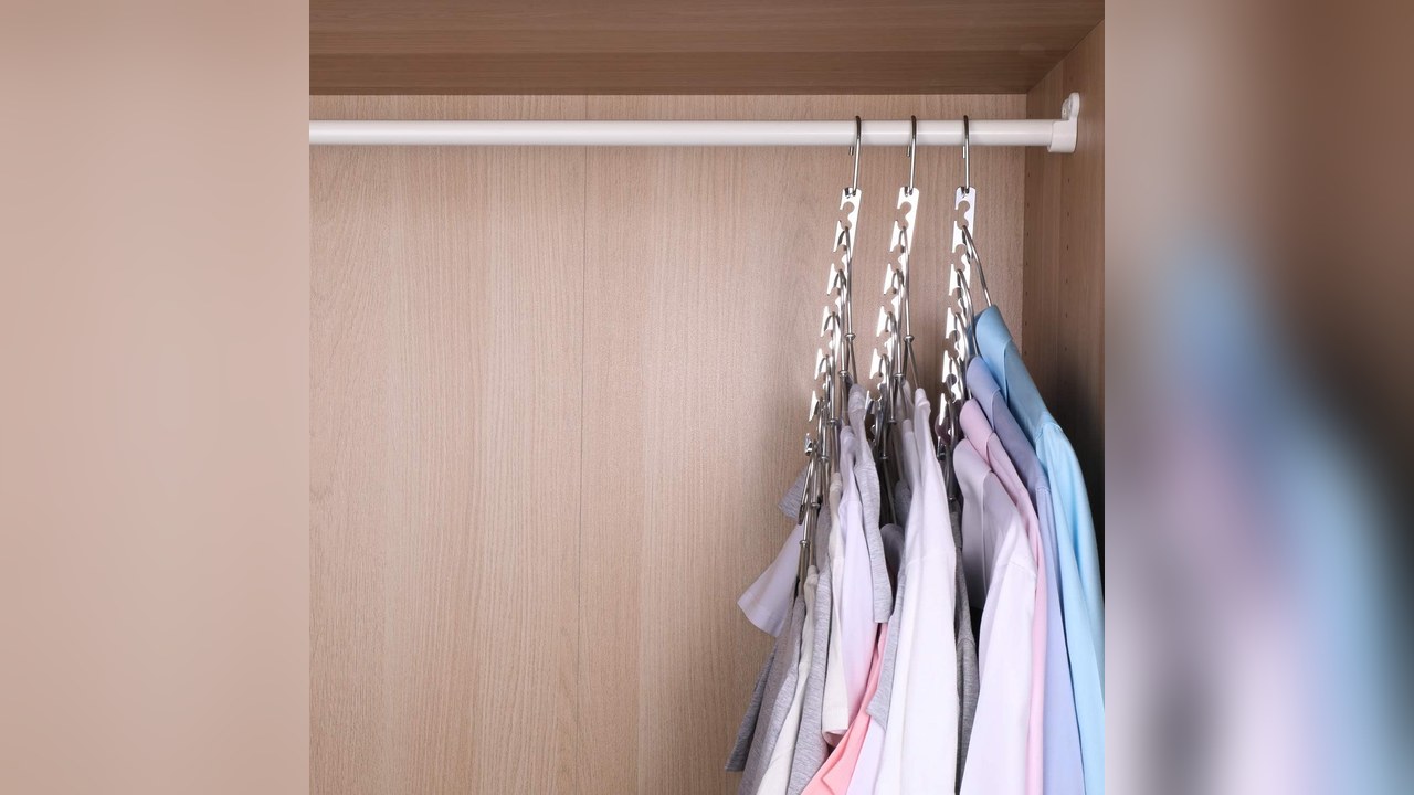 Silver metal cascading space saving hangers holding shirts on a closet rod