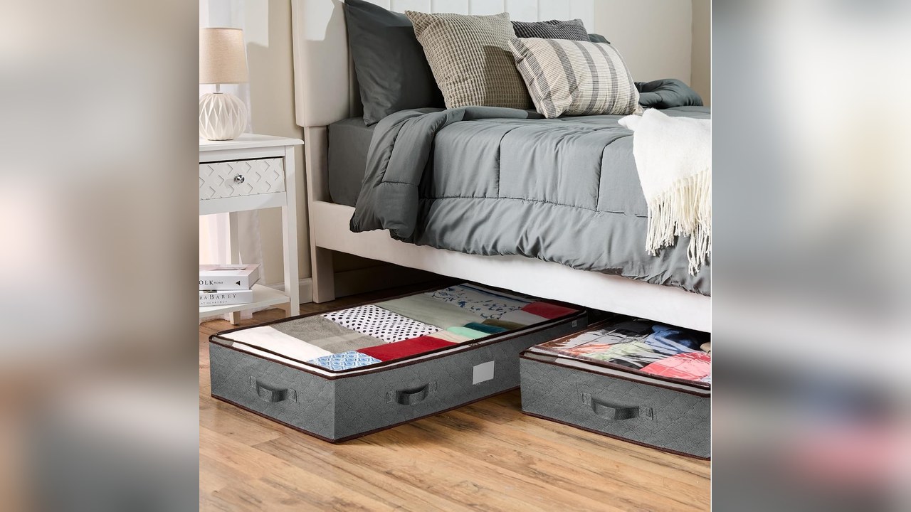 Gray under bed storage bag with clear lid and folded clothes sliding under a bed