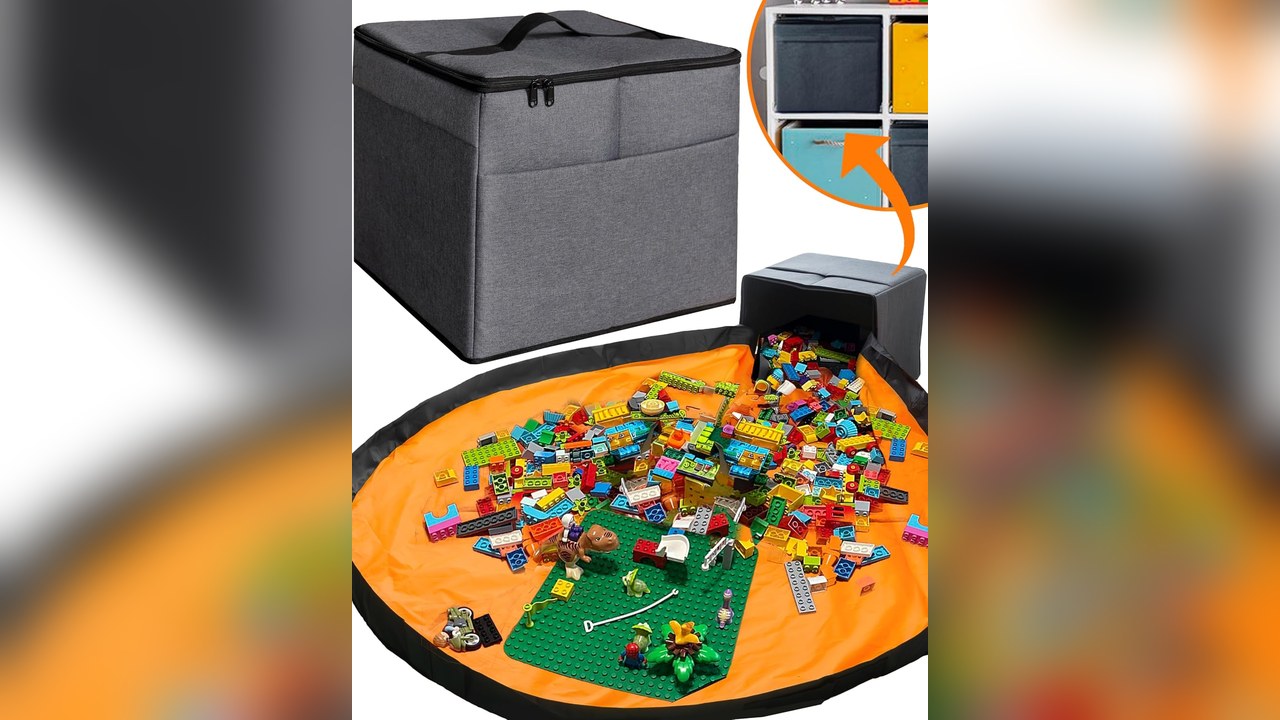 Dark gray square fabric toy storage bin with outer pockets next to an orange play mat covered in building bricks