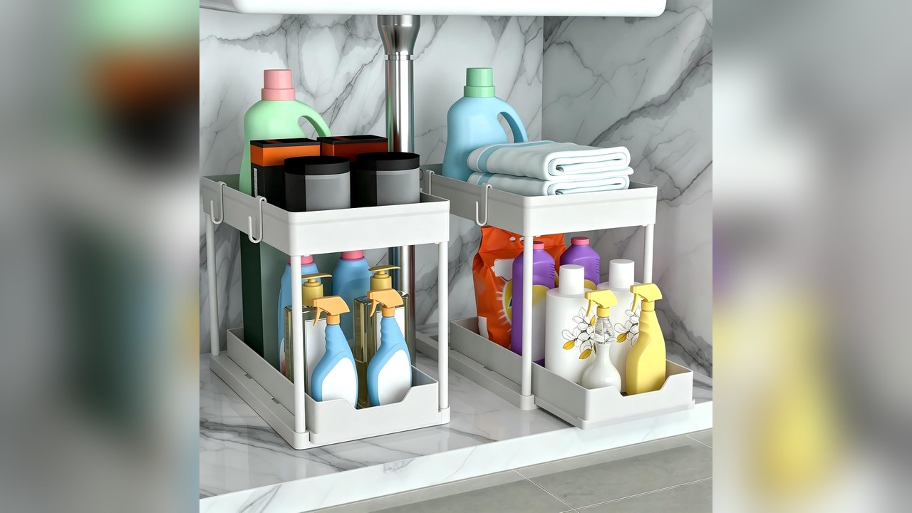 White two-tier sliding under sink organizer with cleaning bottles on both sides of the sink pipe