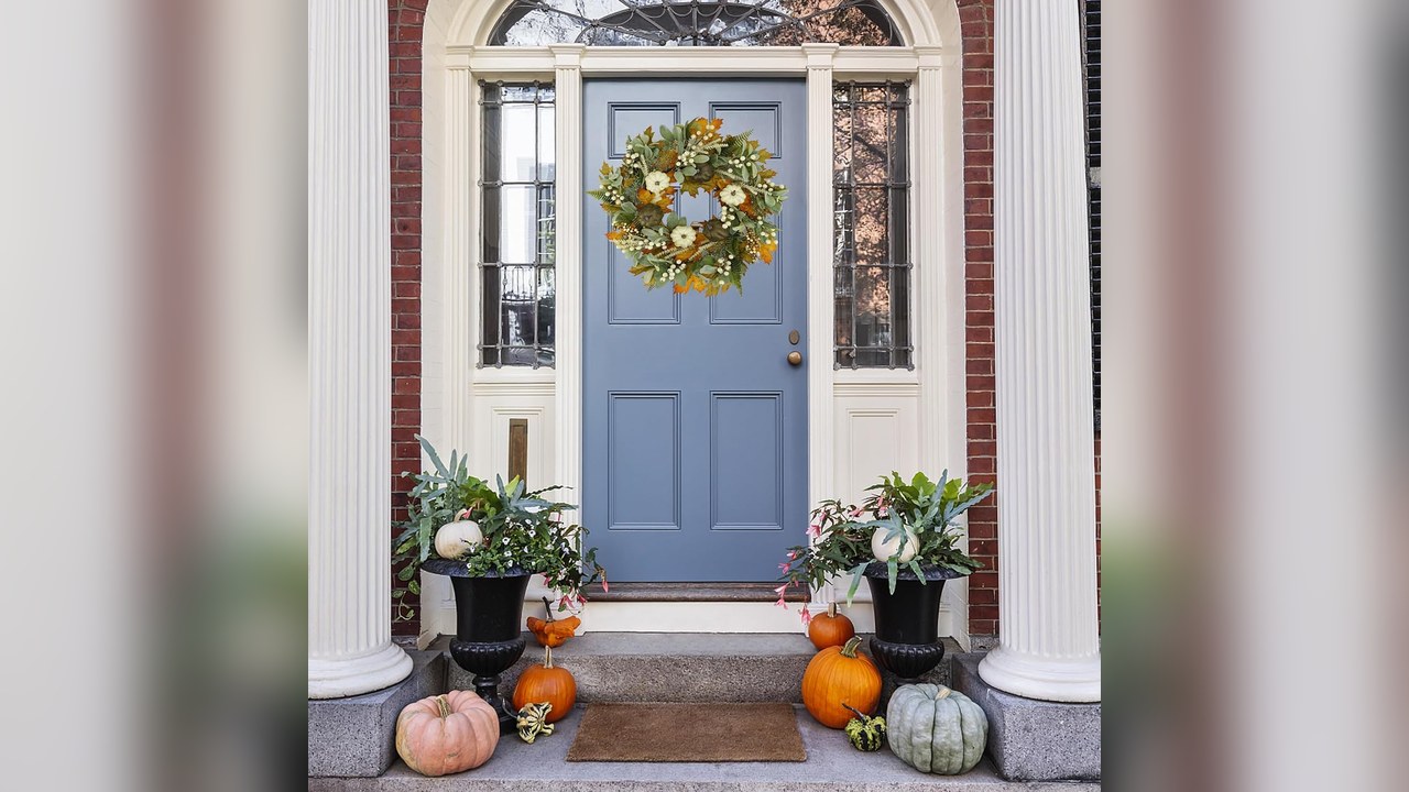 Fall harvest wreath with pumpkins and orange leaves on a front door